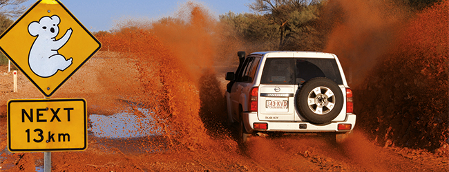 Offroad-Abenteuer durch Australien im Jeep – roter Sand spritzt auf staubigen Wegen. Sprachreisen Australien